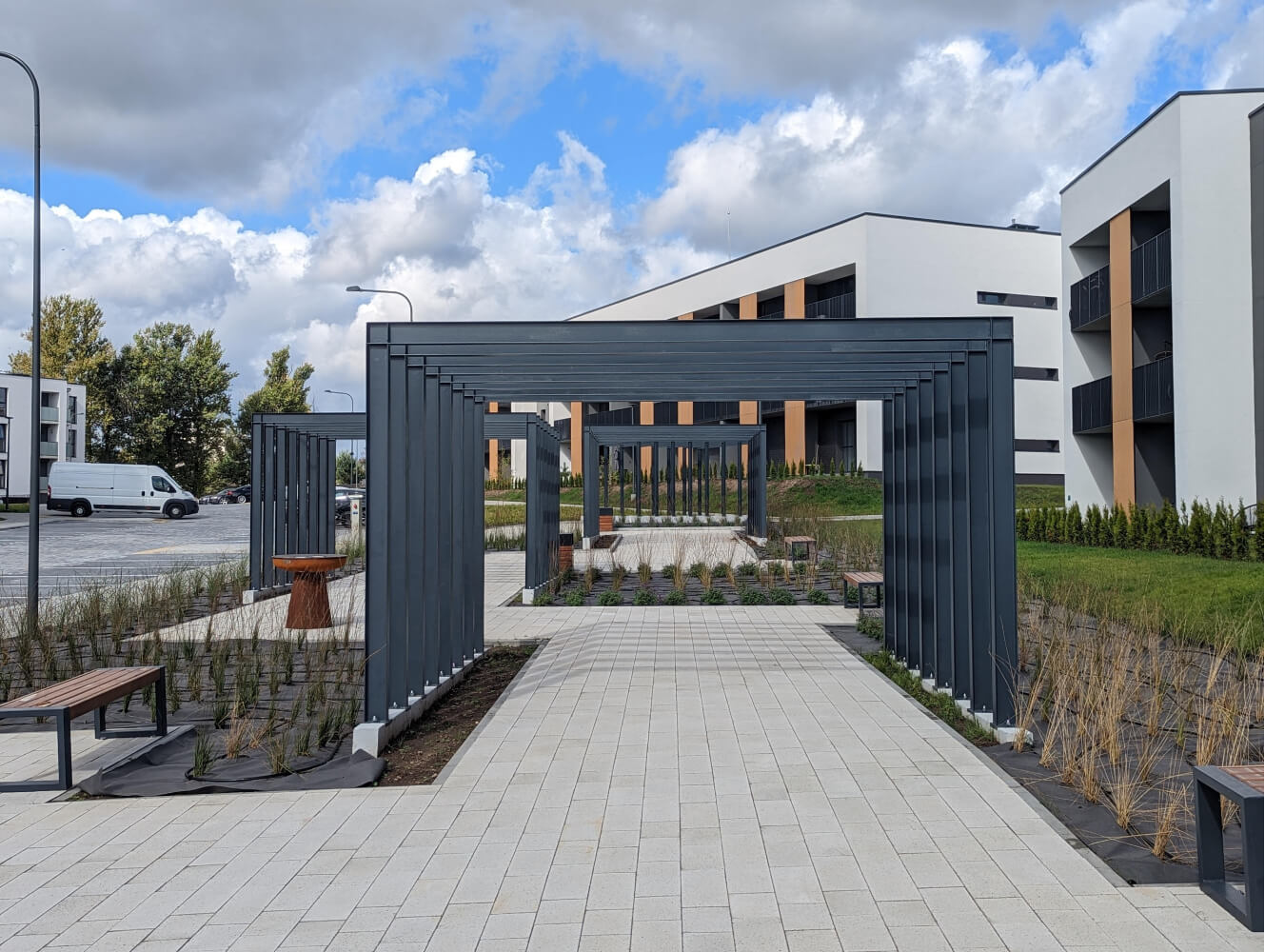 Metalinė pergola tarp daugiabučių pastatų, vertikalus kraštovaizdžio projekto vaizdas